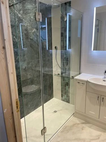 Walk-in glass shower with dark stone wall tiles