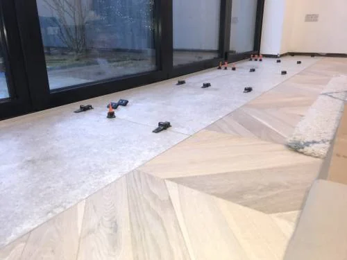 Herringbone floor being installed beside large glazed doors